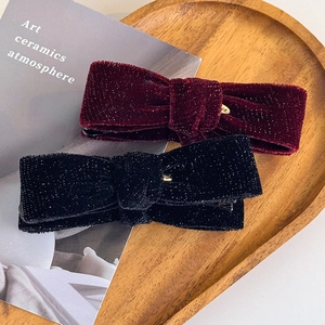 Sparkly velvet bow banana hair clips in burgundy and black on a wooden tray