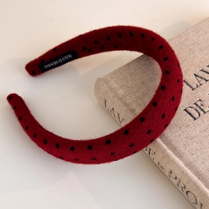 Detailed close-up of a handmade red polka dot headband with a velvet-like texture finish