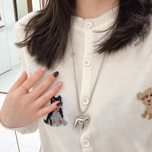 Polished silver horse pendant on a long bead chain necklace worn with a cardigan