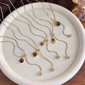 Golden snake chain necklaces with various tiger eye stone pendants in a display tray