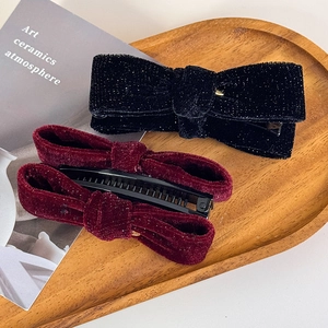 Close-up of vintage velvet bow hair clips with shimmering gold glitter and rich burgundy texture