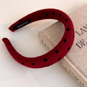Detail view of handmade red polka dot headband with thick velvet texture and inner label