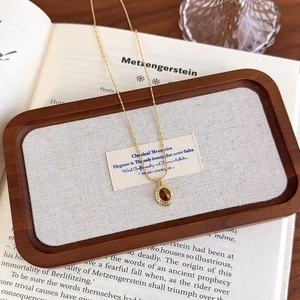 Gros plan du pendentif en pierre oeil de tigre avec bords dorés sur une chaîne vintage