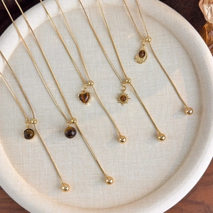Golden tiger eye stone necklaces with heart and sun pendants on round fabric tray