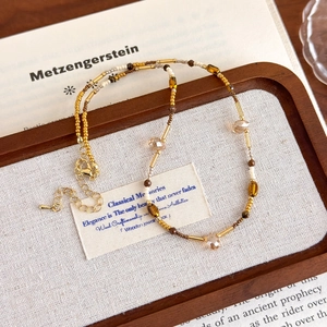 Détail du collier ras du cou en œil de tigre avec perles dorées et pendentif
