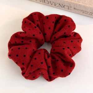 Close-up of a plush red polka dot scrunchie on a white background with a book