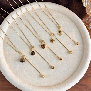 Macro shot of gold snake chains featuring five assorted tiger eye stone pendants on a tray