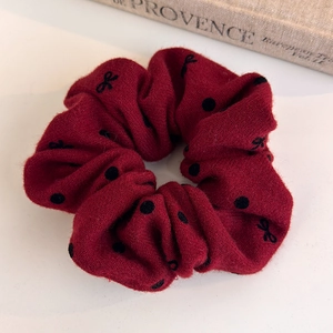 Close-up of deep red polka dot scrunchie in soft velvet fabric for hair styling