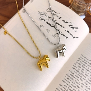 Close-up of gold and silver Dala horse pendants on bead chains atop a book