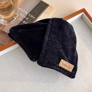 Detailed texture of black corduroy fabric featuring a brown leather Sweet bear patch label
