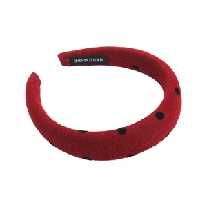 Red headband with black polka dots featuring a thick felt texture and handmade label