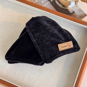 Close-up of black velvet earmuff with brown leather tag in a cozy home setting