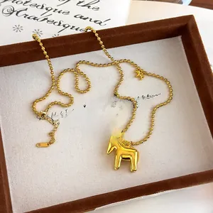 Macro shot of a golden Dala horse pendant on a bead chain necklace inside a jewelry box