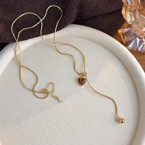 Detail of adjustable gold snake chain with heart-shaped tiger eye stone and metal bead