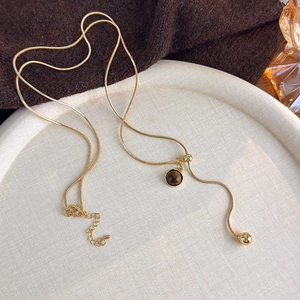 Detail of tiger eye stone pendant on a gold snake chain necklace for autumn style