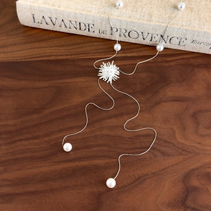 Détail d'un collier lariat argenté avec pendentif flocon et perles sur un livre ancien