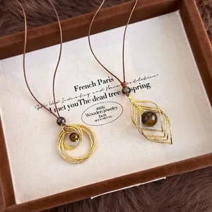 Pendentifs en œil de tigre doré avec designs de cercles et feuilles sur cordons bruns