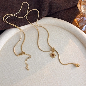 Detailed macro view of gold snake chain necklace with tiger eye sunburst pendant