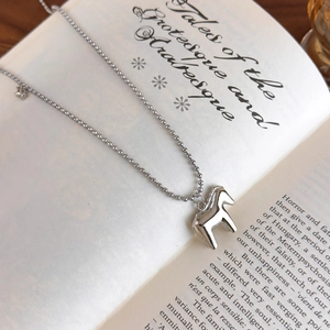 Close-up of silver bead chain necklace with Trojan horse pendant on vintage book