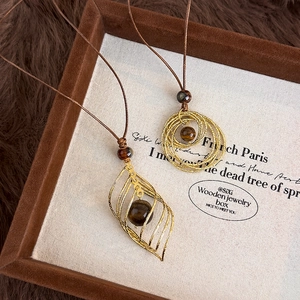 Vue détaillée des colliers vintage avec pierre œil de tigre et pendentifs dorés