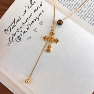 Close-up of golden cross pendant with tiger eye bead on vintage book background