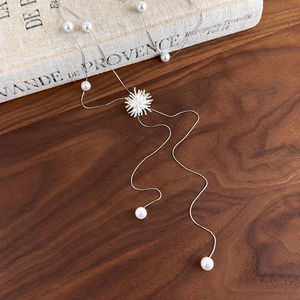 Détail macro du collier à pampilles perles argentées avec pendentif étoile scintillante sur livre