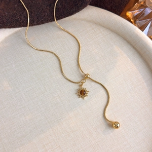 Detail of sunburst pendant with tiger eye stone and gold-plated snake chain necklace