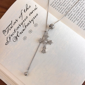 Macro shot of silver gothic cross pendant with tiger eye stone on open vintage book