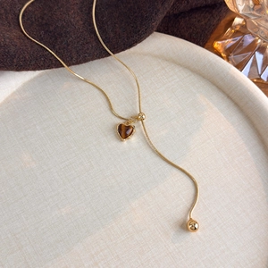 Detail of heart-shaped tiger eye stone pendant on golden snake chain necklace