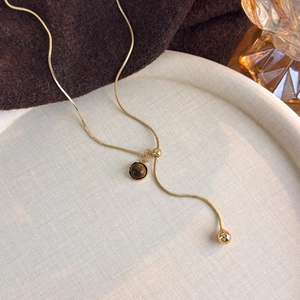 Detailed shot of golden snake chain necklace with tiger eye stone and polished bead