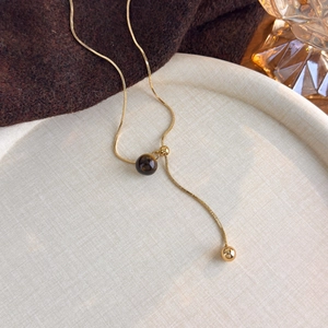 Detail shot of a golden tiger eye stone necklace on a tray with warm aesthetic tones