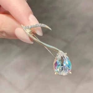Détail d'une broche note de musique ornée d'un grand cristal irisé en forme de poire
