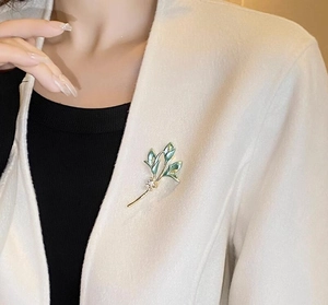 Détail d'une élégante broche muguet avec boutons blancs sur le revers d'un manteau blanc