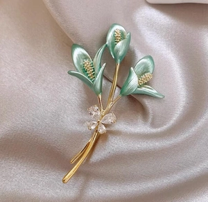 Détail de la broche fleur de lys avec pétales en émail vert et papillon en zircon