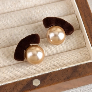 Detail of vintage velvet earrings with a champagne faux pearl in a walnut jewelry box
