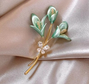 Broche fleur de lys exquise avec pétales en émail vert et cristaux sur soie champagne