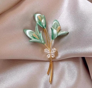 Broche fleur de lys élégante avec bourgeons en émail vert et nœud en zircon sur satin