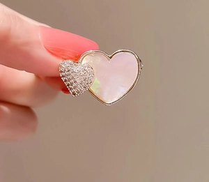 Détail de la broche double cœur avec nacre irisée et diamants pavés élégants