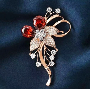 Broche fleur luxueuse en or rose avec cristaux rouges en poire et strass brillants