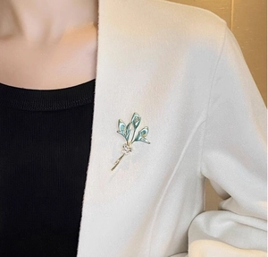 Broche de fleur de lys élégante avec émail vert et strass sur un costume noir