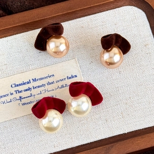 Detailed shot of vintage flocking bow pearl earrings in brown and wine red velvet