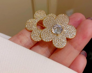 Macro shot of gold-plated double flower brooch with sparkling cubic zirconia pavé