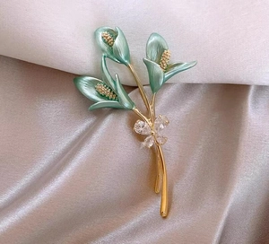 Détail de la broche fleur de calla avec émail vert menthe et nœud en cristaux