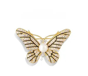 Detail of gold butterfly brooch featuring crystal-encrusted wings and center pearl