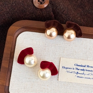 Detail of vintage flocked bow earrings with elegant pearls in burgundy and brown colors