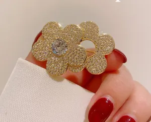 Macro detail of a minimalist double flower brooch with white zircon paving and a gold base