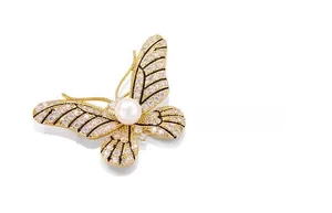 Detail of golden butterfly brooch featuring shimmering crystals and a large white round pearl