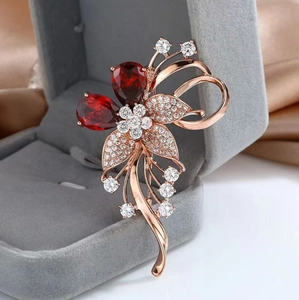 Détail d'une broche fleur de luxe avec pierres poires rouges et finition or rose