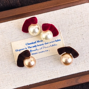 Detail of burgundy and brown velvet bow earrings with faux pearls on linen background