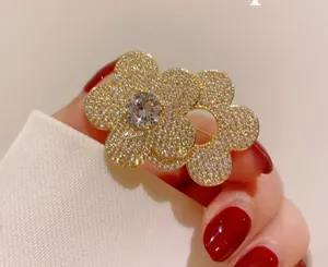 Macro detail of a double flower brooch with micro-paved white zircons on a gold base